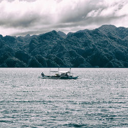 Boat sailing on sea against mountains