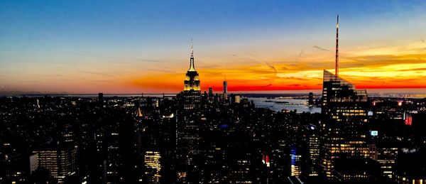 Illuminated buildings against sky during sunset