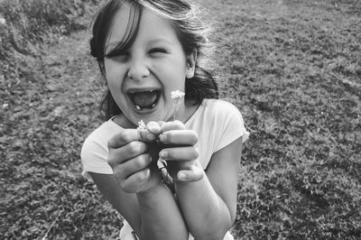 Cheerful girl holding flower on field