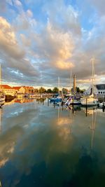 Sailboats moored at harbor against sky during sunset