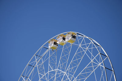 Low angle view of ferris wheel against clear blue sky