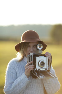 Young woman with camera standing on field