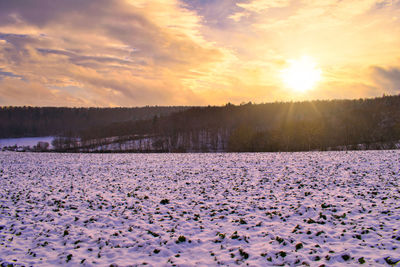 Scenic view of snow covered land against sky during sunset