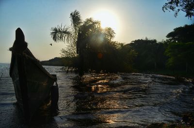 Silhouette person in river against sky during sunset