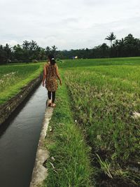 Woman walking on field against sky