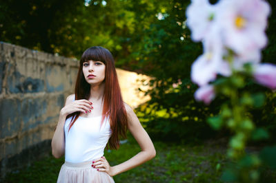 Close-up of flowers against young woman standing at park