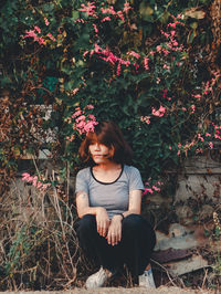 Full length of woman sitting by plants