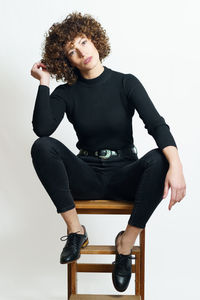 Portrait of young woman sitting against white background