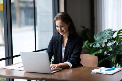 Young woman using phone while sitting on table