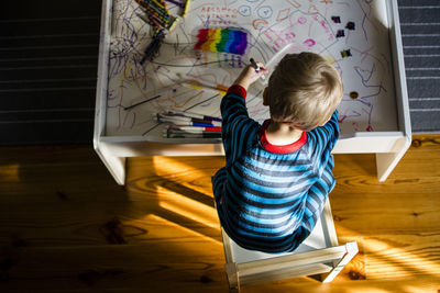 High angle view of boy drawing while sitting on table