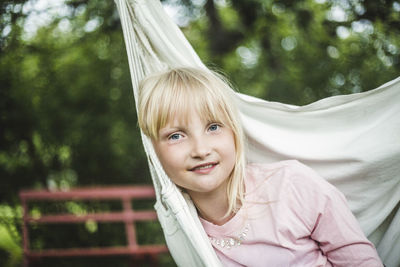 Portrait of smiling girl sitting in white swing in garden