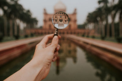 Crop anonymous traveler showing upside down reflection of old stone safdarjungs tomb located in new delhi person