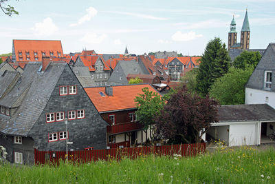 Houses by buildings in town against sky