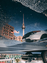 Reflection of fernsehturm on puddle in city
