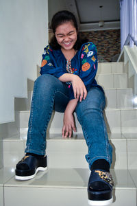 Portrait of a smiling young woman sitting on tiled floor at home
