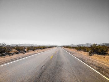 Diminishing perspective of empty road against clear sky during sunny day