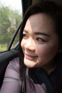 Close-up of smiling woman looking away while traveling in car