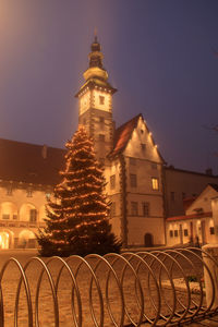 Illuminated christmas tree against building at night