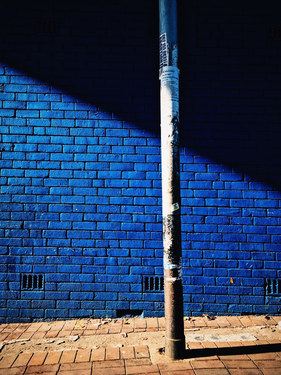 SHADOW OF BLUE WALL ON BRICK BUILDING