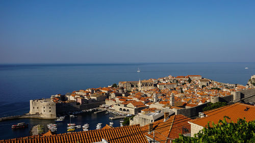 High angle view of townscape by sea against clear sky