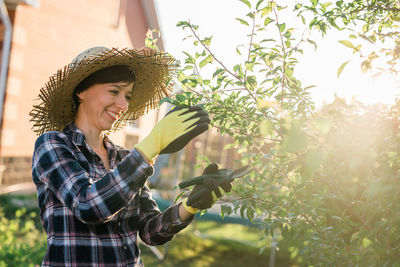 Portrait of young woman standing against plants