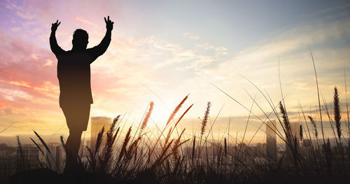 Silhouette person standing on field against sky during sunset