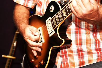 Midsection of man playing guitar