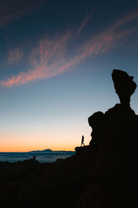 Silhouette of young woman between big rocks during sunset in gran canaria