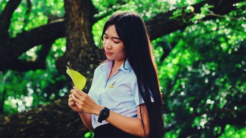 Beautiful woman standing by tree in forest