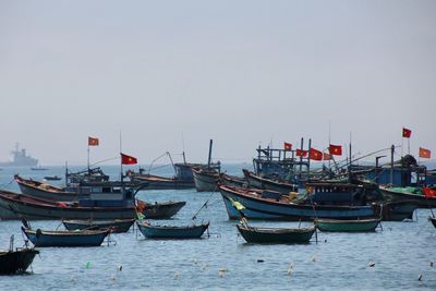 Sailboats moored in harbor against clear sky