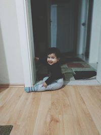 Portrait of woman sitting on hardwood floor at home