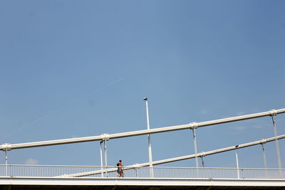 People on bridge against clear blue sky