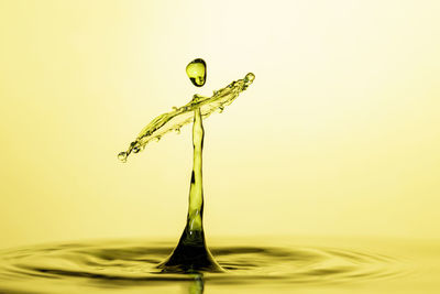 Close-up of drop falling on water against white background