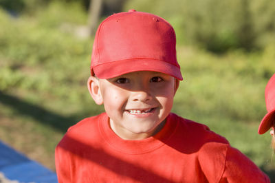 Young boy missing a tooth in red baseball cap smiling at camera