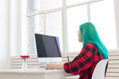 Side view of woman using phone while sitting on table