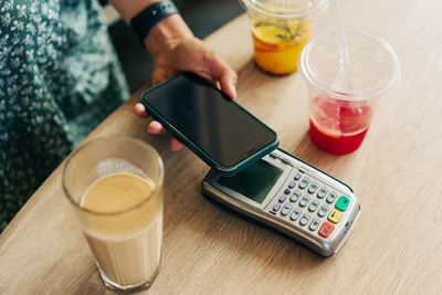 Close-up of contactless mobile phone payment by unrecognizable people at cafe.