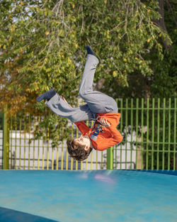 Healthy sport little caucasian boy jumping somersault outdoors nature with copyspace.