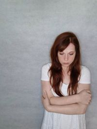 Portrait of young woman standing against wall