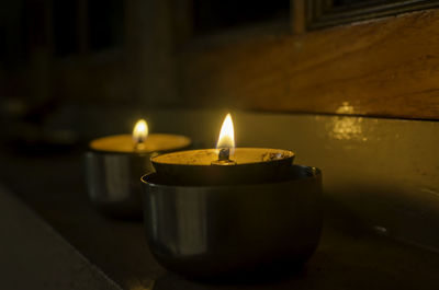 Close-up of illuminated tea light candles in building