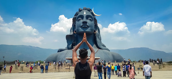 Group of people at statue against cloudy sky