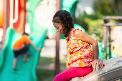 Cute girl playing on slide at playground