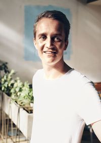 Smiling young man standing at home against wall