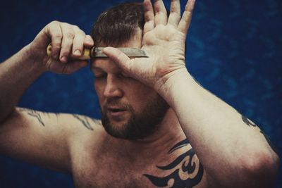 Close-up of shirtless man with hand on swimming pool