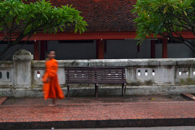 Rear view of man walking on footpath by building