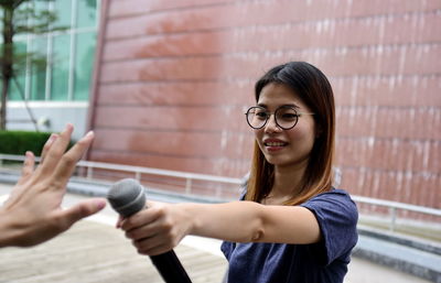 Portrait of smiling woman standing against wall