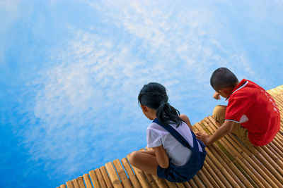 High angle view of siblings sitting on jetty over lake