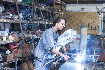 Woman welding metal in factory