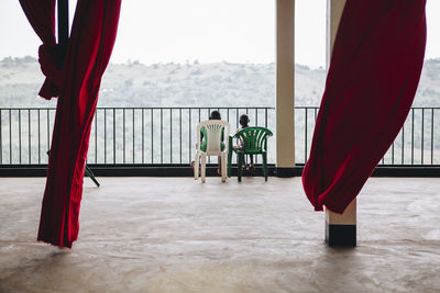 Two child friends sitting and talking together on a balcony look out at the view in kampala, africa.