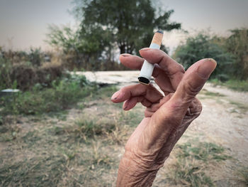 Close-up of hand holding cigarette