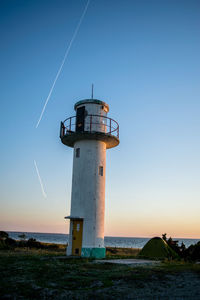 Lighthouse by sea against sky during sunset